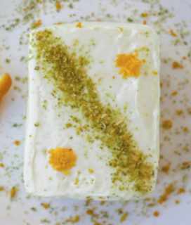 Image of a slice of Amy’s Lemon Ice Box Cake with grated lemon zest and chopped pistashios