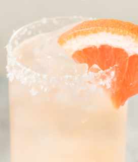 Image of a Tomato Paloma Cocktial in a glass with a grapefruit wedge