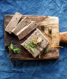 Photo of Three Little Pigs Pâté de Campagne on a wooden board against a blue background 