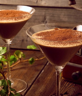 Photo of two Tiramisu Cocktail glasses on a wooden table with an ivy plant