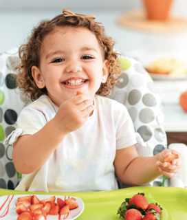 Photo for the Alameda County Community Food Bank. Child sitting in high chair eating strawberries