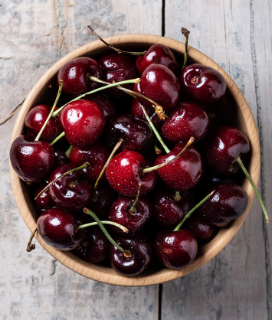 A bowl of Summer Cherries on a wooden table