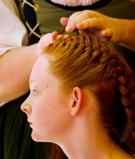 2023 NorCal Renn Faire photo of a young woman having her hair braided