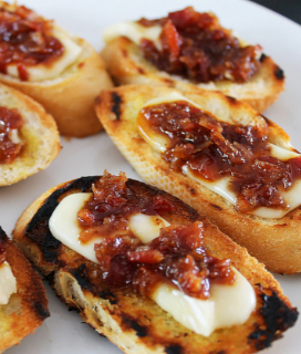Photo of Brie Toasts with Bacon Plum Jam on a white platter 