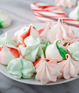 Red and green Peppermint Meringue Kisses on a marble tabletop