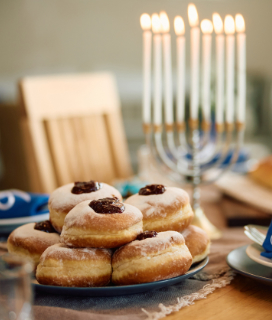 A photo of a table with a menorah and jelly doughnuts for Happy Hanukkah 2023