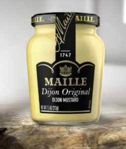 A jar of Maille Dijon Original Mustard sitting on a wooden table