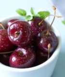 Local Cherries in a white bowl on a table top with a napkin